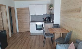 A modern kitchen with wooden paneling and a small dining area. The room is bright and welcoming.