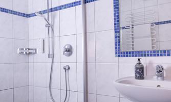 A modern bathroom with a shower and a sink. The walls are decorated with white tiles and blue accents.