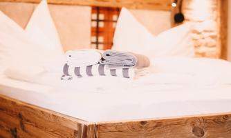 A cozy bedroom with a wooden bed. Folded towels are on the bedspread.