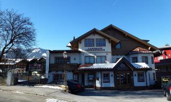 A charming inn with traditional architecture in the mountains. The clear sky and snow-covered mountains in the background create an inviting atmosphere.