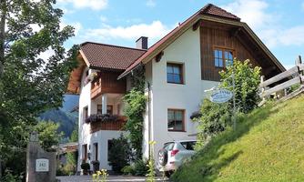 A charming house with wooden elements and a well-maintained garden. The surroundings are green and invite relaxation.