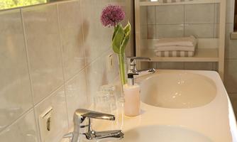 A modern bathroom with two sinks. A fresh flower and clean towels give the space an inviting atmosphere.