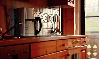 A cozy kitchen with wooden cabinets and a modern coffee machine. The light streams through the window, creating an inviting atmosphere.