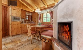 A cozy kitchen with wood paneling and a fireplace. The room has a rustic charm and plenty of natural light.