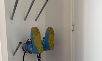 A pair of colorful shoes hangs on the wall. They are secured with a strap and display the sole facing up.