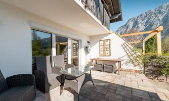 An elegant terrace with comfortable furniture offers a stunning mountain view. The sunny atmosphere invites relaxation.