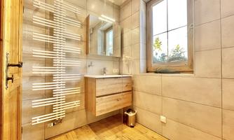 A modern bathroom with wood and tile design. It features a window, a washbasin, and a towel radiator.