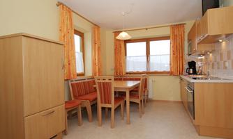 A bright kitchen with wooden cabinets and a dining area. The large windows let in plenty of light.