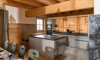 A modern kitchen with wooden shelves and an elegant kitchen island. The walls are covered with natural wood, creating a warm atmosphere.