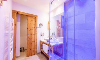 A modern bathroom with a glass shower and soft lighting effects. The warm wooden elements create an inviting atmosphere.