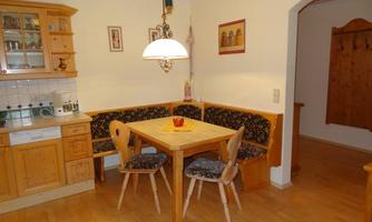 A cozy kitchen with wooden furniture and a dining table. In the corner, there is a seating area with a table and chairs.