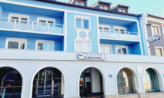 A light blue building named "Pension Schachner". It has several balconies and large windows.