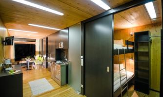 A modern apartment with wooden interior and a cozy ambiance. The open kitchen and sleeping area provide an inviting atmosphere.