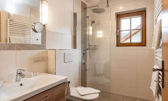 A modern bathroom with a shower cabin and bright tiles. The room is well-lit and offers a pleasant atmosphere.