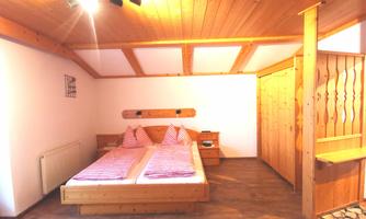 A cozy room with two single beds and wood paneling. The walls are light, and the lighting creates an inviting atmosphere.