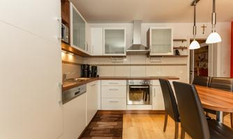 A modern kitchen with bright furniture and wooden surfaces. The room is well lit and has plenty of storage space.