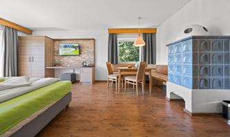 A modern room with a large bed and a dining area. The room has bright colors and a TV on the wall.