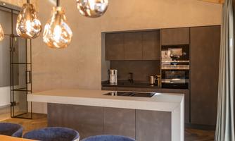 Modern kitchen with sleek appliances and a large kitchen island. Soft lighting creates a cozy atmosphere.