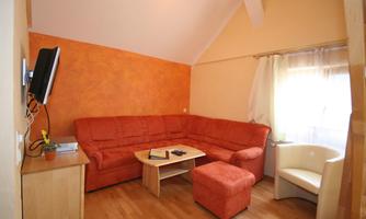 A cozy living room corner with a red sofa and a small table. The room has bright walls and plenty of daylight.