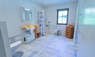 A modern bathroom with bright tiles and natural light sources. It is equipped with a shower, a sink, and a toilet.