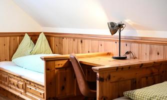 A cozy room with wood paneling and two beds. There is a lamp on the table that provides pleasant lighting.