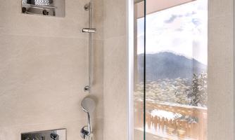 A modern shower with a glass partition and a rain showerhead. In the background, a beautiful landscape can be seen.