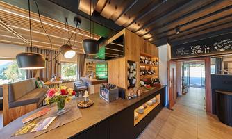 A modern café with wooden decor and an inviting atmosphere. Fresh flowers and various drinks are available on the counter.
