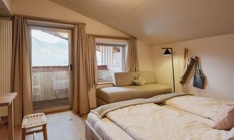 A cozy room with two beds and a sitting area. Large windows offer a view of the mountains.