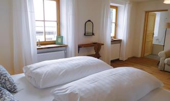 A comfortable room with two beds and large windows. The space is bright and cheerfully furnished.