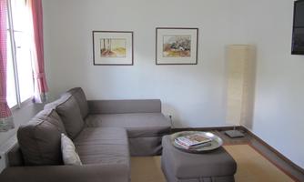 A cozy living room with a gray sofa and a coffee table. Two pictures are hanging on the wall, and a floor lamp provides additional light.