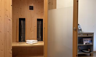A cozy sauna room with wood paneling and a seating area. Folded towels are on the bench, while everything is designed in a relaxing ambiance.