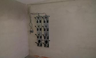 A gray wall with a mounted holder system. Several compartments for devices or accessories are visible.