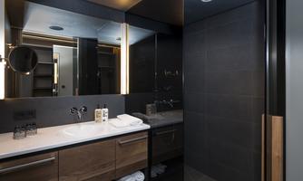A modern bathroom with a stylish shower and a wooden vanity. The walls are painted in dark gray, creating an elegant atmosphere.