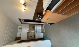 A small kitchen with modern appliances like a microwave and a coffee maker. The walls are light, and the floor has a carpet.