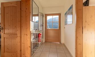 A modern entrance area with wood details and a large window that looks out at the mountains. A mirror and a picture are hung on the wall.