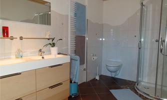 A modern bathroom with a shower, a sink, and a toilet. The walls are bright, and the furnishings are functional and stylish.