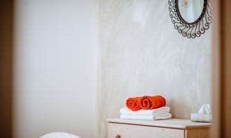A cozy room with a mirror and a wooden wardrobe. On the wardrobe are towels in orange and white.