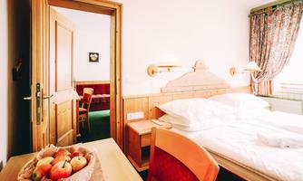 A cozy room with a double bed and a table with apples on it. Through the open door, another room is visible that looks inviting.