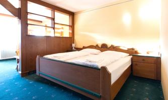 A cozy bedroom with a large bed and wooden furniture. The room is brightly and cheerfully decorated.