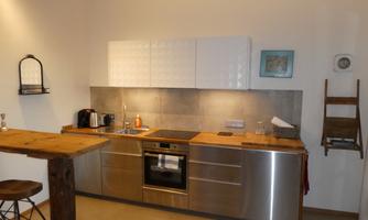 Modern kitchen with stainless steel surfaces and wood details. It features cooking utensils and stylish decor.