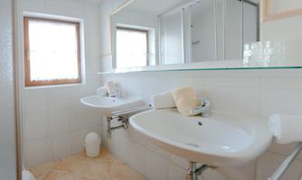 A modern bathroom with two sinks and large windows. The bright tiled wall creates a clean and friendly atmosphere.