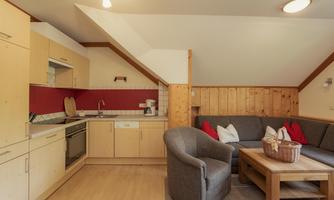 A cozy kitchen with a seating area. The room has a modern design with wood and red accents.