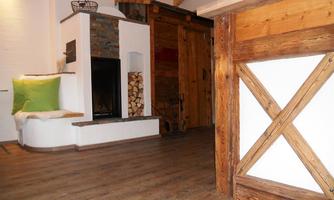 A cozy living space with a wood stove and a rustic wood design. The decor conveys a warm and inviting atmosphere.