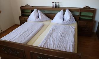 A bedroom with two single beds and pillows. The wooden furniture is designed in a classic style.