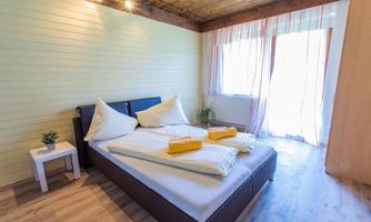 A cozy bedroom with a double bed and bright bedding. Large windows let in plenty of light and offer a view outside.
