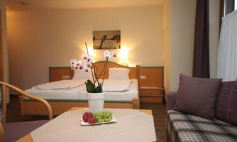 A cozy hotel room with a double bed and pleasant lighting. Fresh fruit and an orchid in a pot are on the table.