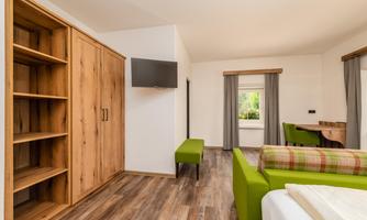 A modern room with wooden furniture and a green armchair. The space is bright and cheerfully designed.