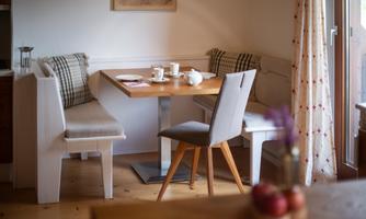 A cozy dining area with a wooden tabletop, surrounded by comfortable benches and a chair.