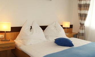 A cozy bedroom with a double bed and two nightstands. The walls are light, and there is modern window decoration.