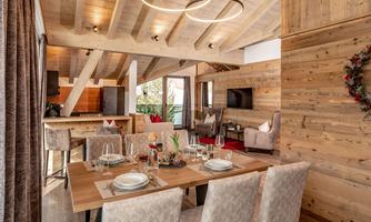 A stylish dining room with a large wooden table and elegant chairs. The modern wooden walls and ceiling beams create a cozy atmosphere.